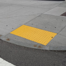 Sidewalk and pedestrian ramp with yellow safety metal